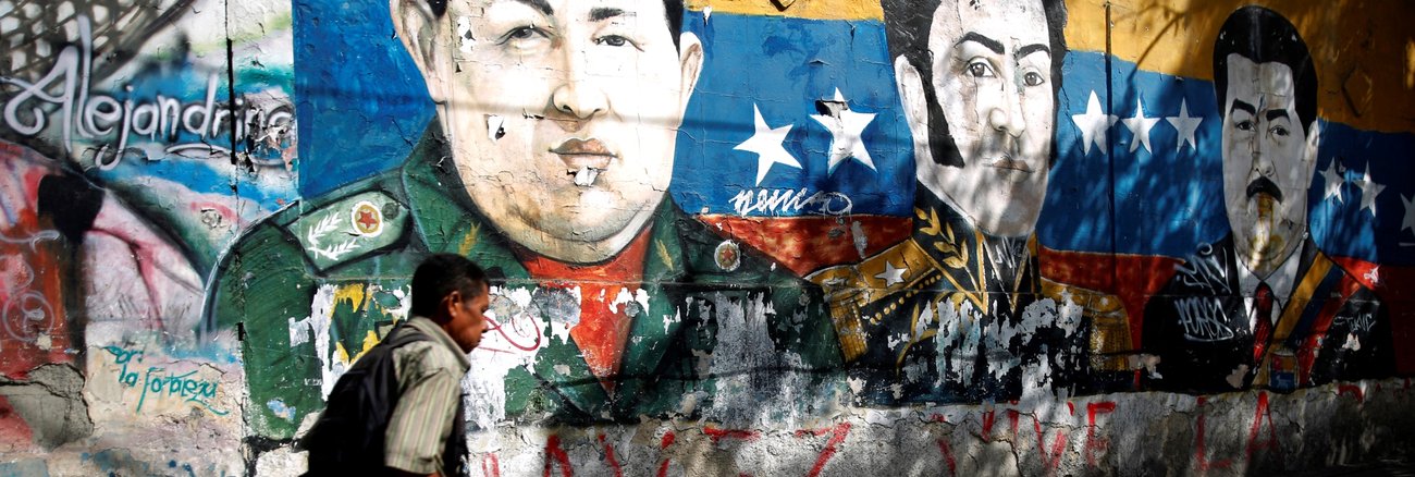 Ein Mann läuft am 30. Januar 2019 in Caracas, der Hauptstadt von Venezuela, an einem Graffiti vorbei, das die Köpfe von Hugo Chavez, Simon Bolivar und Nicolas Maduro zeigt © REUTERS/Carlos Barria
