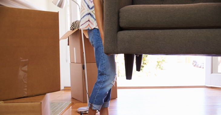 Eine Frau in Jeans trägt ein Sofa © iStockphoto.com/monkeybusinessimages